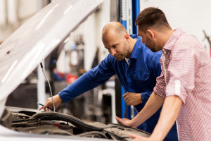 An auto mechanic explains car problems to a car owner.